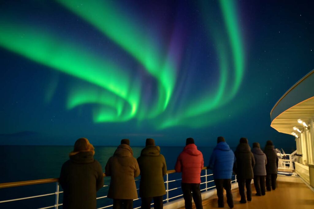 Passengers watching Northern Lights from cruise ship deck under clear Arctic sky