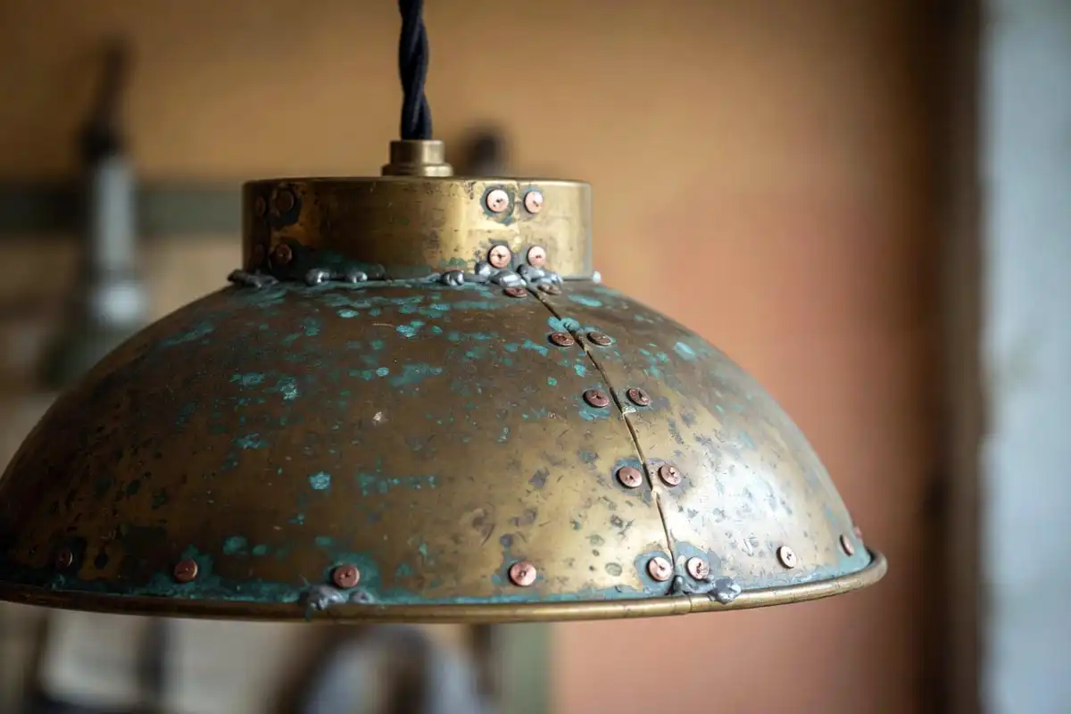 An authentic brass industrial pendant light showing patina, rivets, and hand soldered seams