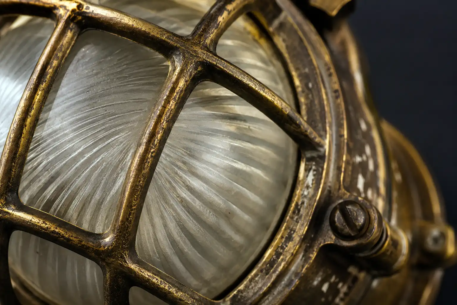 Close up of a salvaged brass bulkhead light cage and thick frosted glass lens