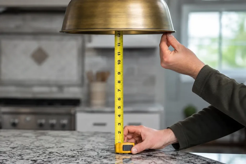 Tape measure checking pendant hanging height above a kitchen island countertop before installation