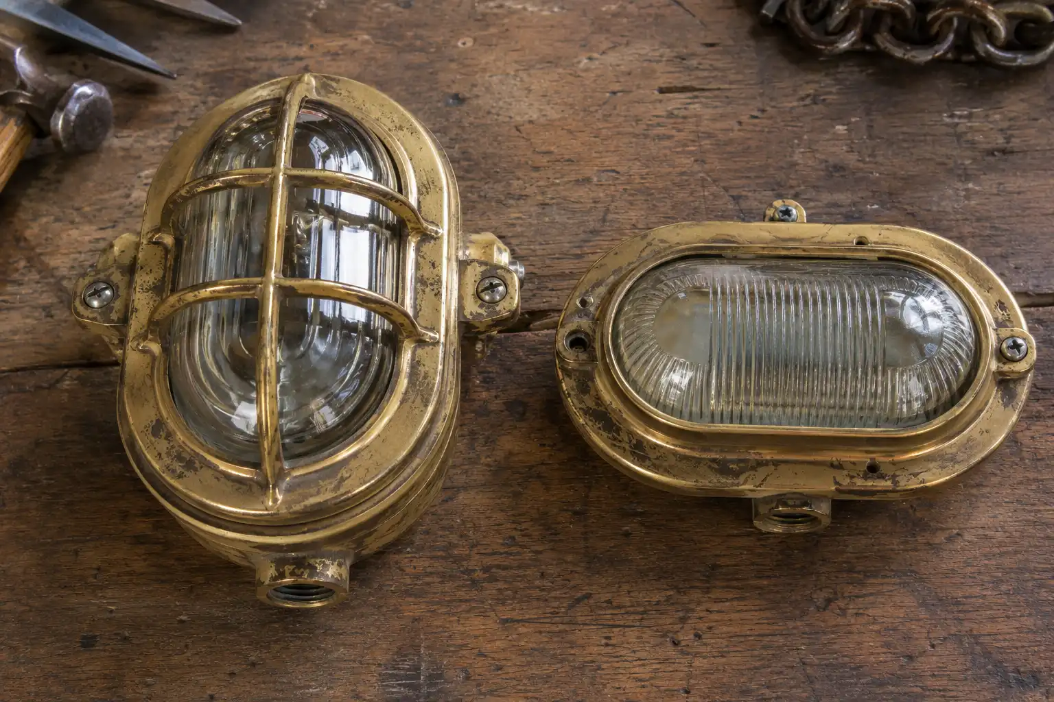 Salvaged brass ship light bodies showing depth difference on a workbench in Chattogram, Bangladesh