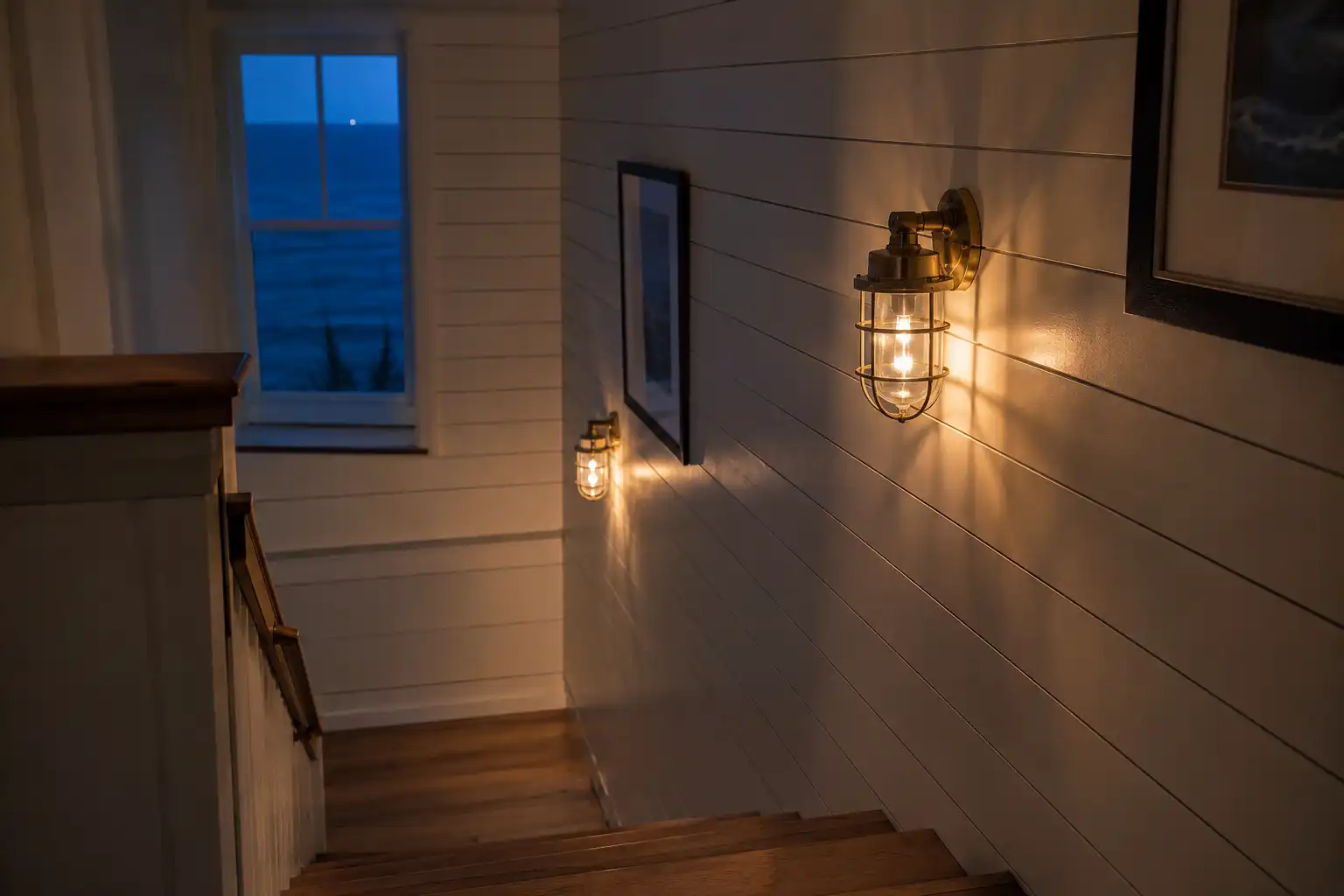 Two salvaged brass ship passageway lights lighting a coastal home stairwell wall