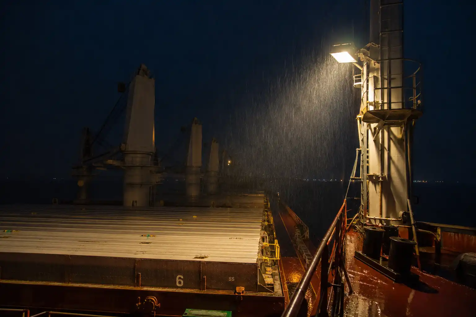 Deck floodlight on a bulk carrier lighting steel cargo hatches at night before breaking in Bangladesh