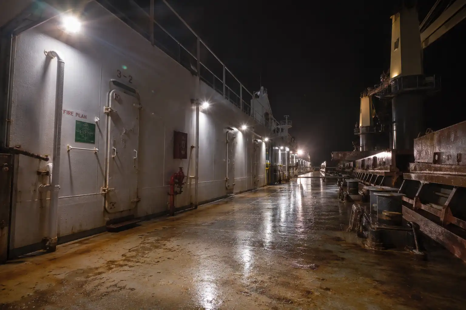 Steel deck lights spaced along a cargo ship bulkhead at night, sourced from Chattogram